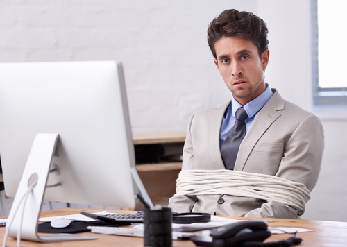 A person in a suit tied up with rope at their desk.