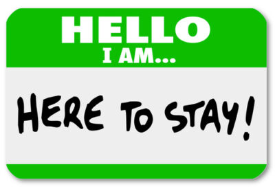 Leave Anytime. Stay Because You Want To 1 A name tag with a bold green top border and white bottom featuring the text 'HELLO I AM... HERE TO STAY!' in handwritten black lettering.